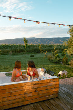 Two women relax in a hot tub with a view of the mountains