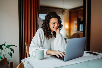 Young caucasian woman working on laptop from home	