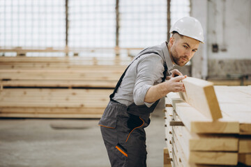 Carpenter checking wooden planks in a timber warehouse