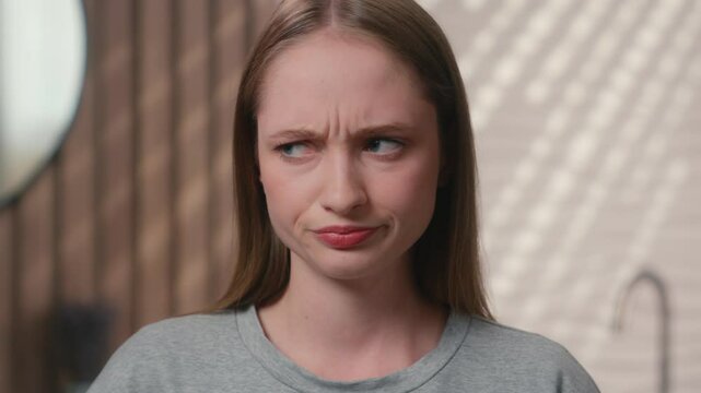 Caucasian woman offended female sad upset displeased angry frowning face girl teenager looking at camera portrait bad mood grimace worried negative expression disappointed in home bathroom hotel bath