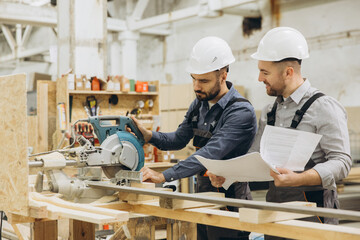 Engineers reading blueprint and using circular saw for modular building project