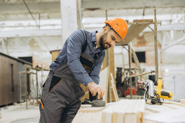 Carpenter sanding wooden plank in modular building factory