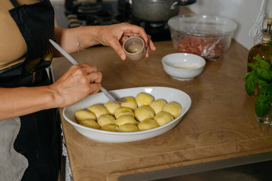 Woman spreading butter on dough balls by filo