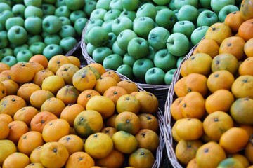 food fruits background of pile of juicy, bright green colored apples and ripe orange mandarin, tangerine in wicker basket. Autumn crop harvest. Fall season. Gandagana  rural tourism festival in Batumi