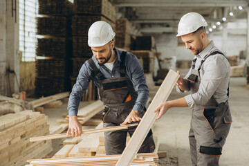 Carpenters working and examining wooden planks in workshop
