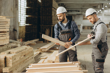 Carpenters working with wooden planks in timber warehouse