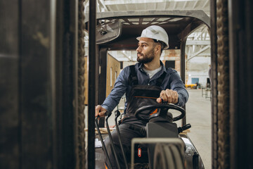 Construction worker driving forklift in modular building factory