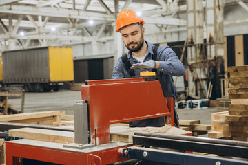 Carpenter operating woodworking machine in factory for modular building