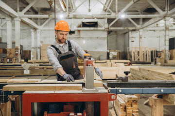 Carpenter cutting wooden plank using saw in workshop for modular building