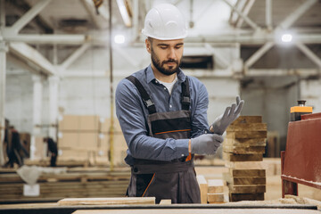 Carpenter wearing protective gloves in woodworking factory