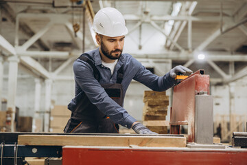 Obraz premium Carpenter working with wood plank and saw in factory for modular building