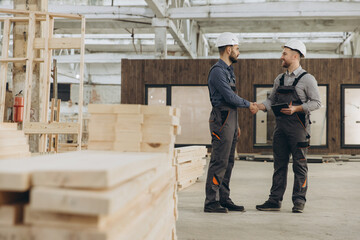 Construction workers shaking hands in modular building factory