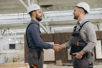 Engineers shaking hands in modular building factory