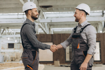 Construction workers shaking hands at modular building factory