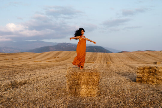 Carefree female spinning on hayrick in field