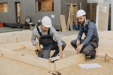 Carpenters building wooden frame for modular house in workshop