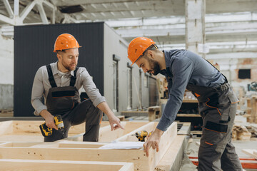 Construction workers building wooden frame in factory
