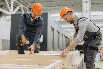 Construction workers building wooden frame in factory for modular building