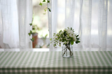 Fototapeta premium Green checkered tablecloth over white surface, sunlight filters softly through window