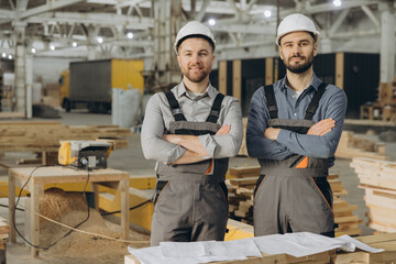 Construction workers posing with arms crossed in modular building factory