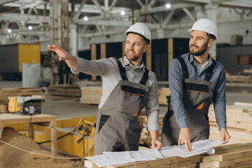 Engineers discussing building project using blueprint in modular house factory