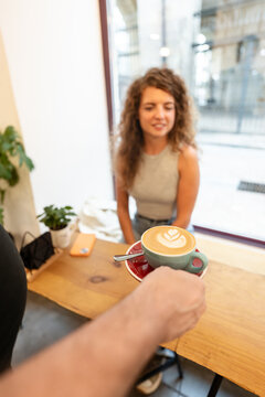 Barista serving latte art coffee to customer in cafe