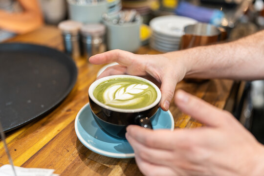 Barista serving a cup of matcha latte with latte art
