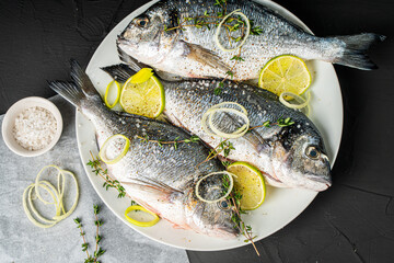 Dorado fish with leeks, lemon, lime on a white plate ready to cook on a black background