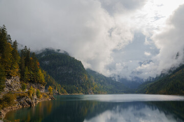 Scenic view of idyllic lake in Alps in autumn, mountains in clouds
