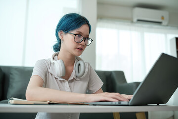 A woman wearing glasses and headphones is typing on a laptop