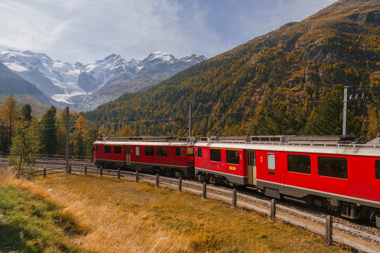 Red train on mountain pass in Swiss Alps in autumn 