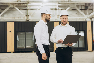 Engineers using laptop in modular building factory