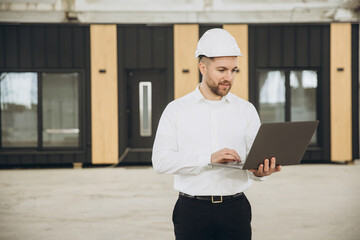 Architect using laptop in front of modular building