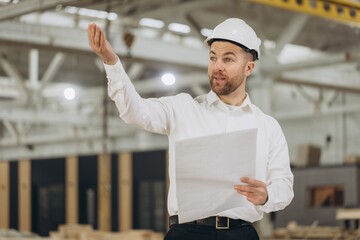 Construction supervisor giving instructions holding blueprints in modular building factory