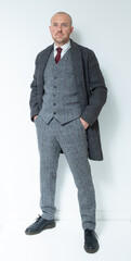 A modern corporate man in a tailored tweed three piece suit. Grey tweed knit business suit for lawyers, bankers and for men with high power positions. Corporate barrister and peaky blinders cos play.