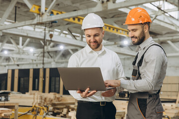 Engineers using laptop, inspecting prefabricated house in modular building factory