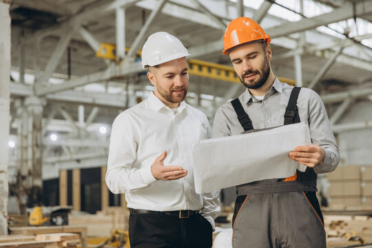 Engineers discussing blueprint in modular building factory