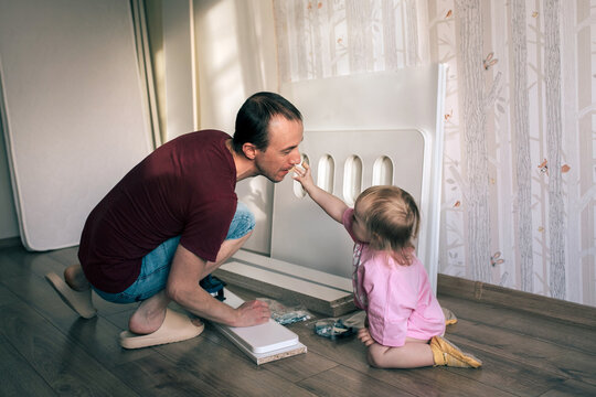 Father and daughter assemble a new bed using a screwdriver.