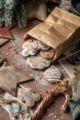 Christmas gingerbread cookies in kraft paper bag on rustic table with fir branches, spices, christmas decorations. Xmas homemade gifts, atmospheric holiday