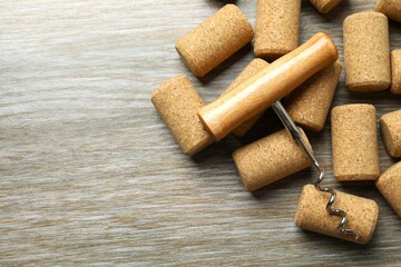 Wine corks with corkscrew on wooden background 