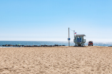 A lifeguard tower on a sandy beach in Los Angeles, with an ocean backdrop and sunny skies.