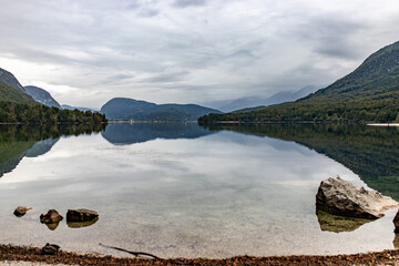 A serene view of Lake Bohinj, Slovenia, with still waters and mountains creating a stunning reflection