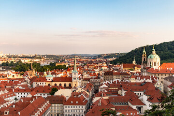 An enchanting view of Prague from the castle, featuring iconic landmarks and red rooftops during sunset.
