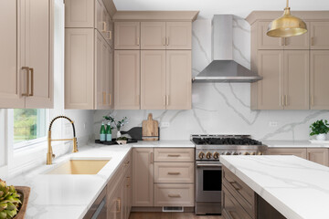 A kitchen detail with brown cabinets, marble countertop and backsplash, wood island, and gold...