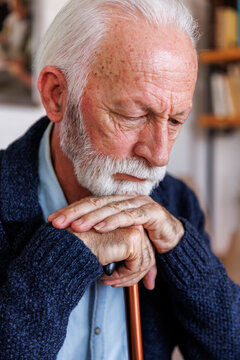 Closeup of contemplative senior man leaning on cane