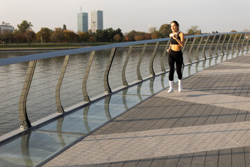 Morning jogger enjoys serene run along the waterfront in a vibrant city, with reflections...