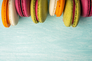 Multi-colored macaroons are stacked. Cherry, pistachio and mango macaroons on a light blue...