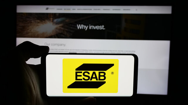 Stuttgart, Germany - 11-07-2024: Person holding cellphone with logo of industrial company ESAB Corporation on screen in front of business webpage. Focus on phone display.