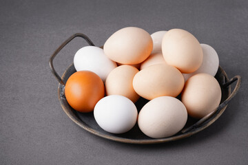 Freshly gathered eggs in a rustic bowl displayed on a textured gray countertop