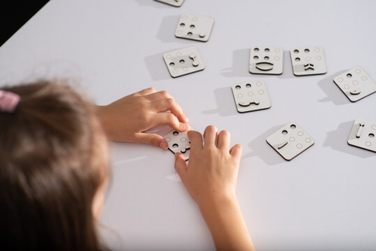 Little faceless child touches punctuation mark in Braille